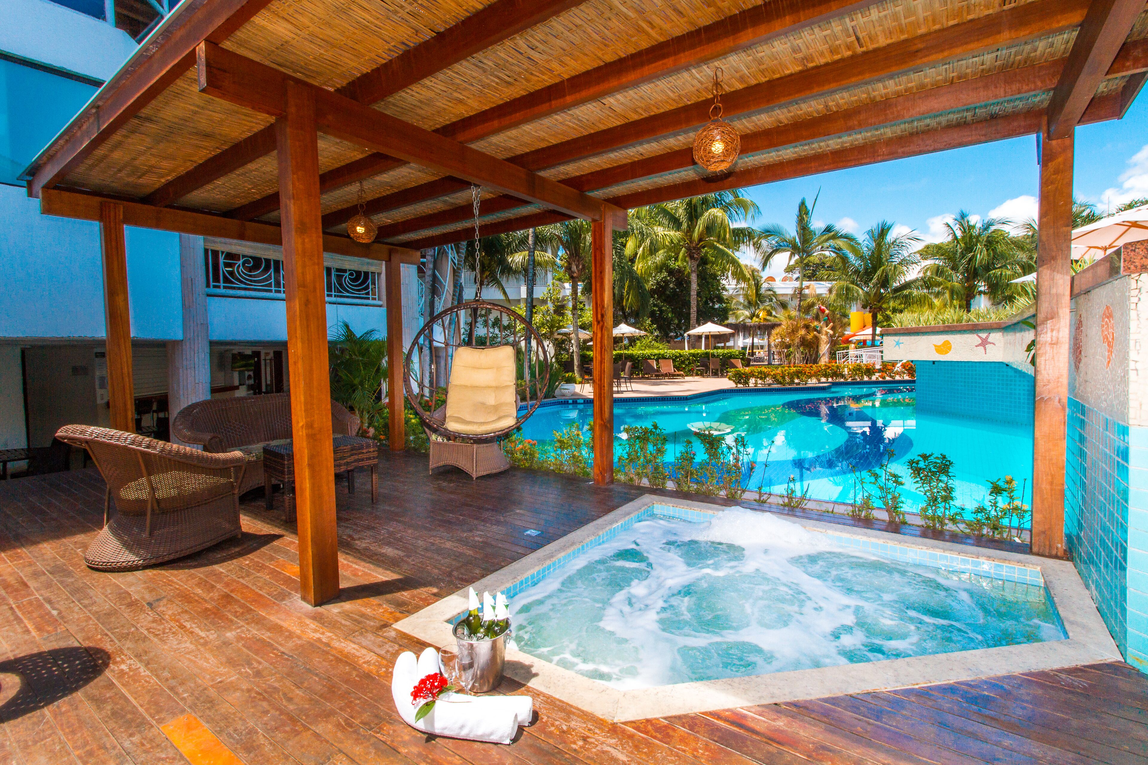 A rooftop pool area with a hot tub, lounge chairs, and a view of the pool.