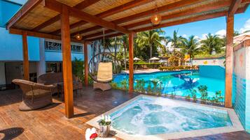 A rooftop pool area with a hot tub, lounge chairs, and a view of the pool.