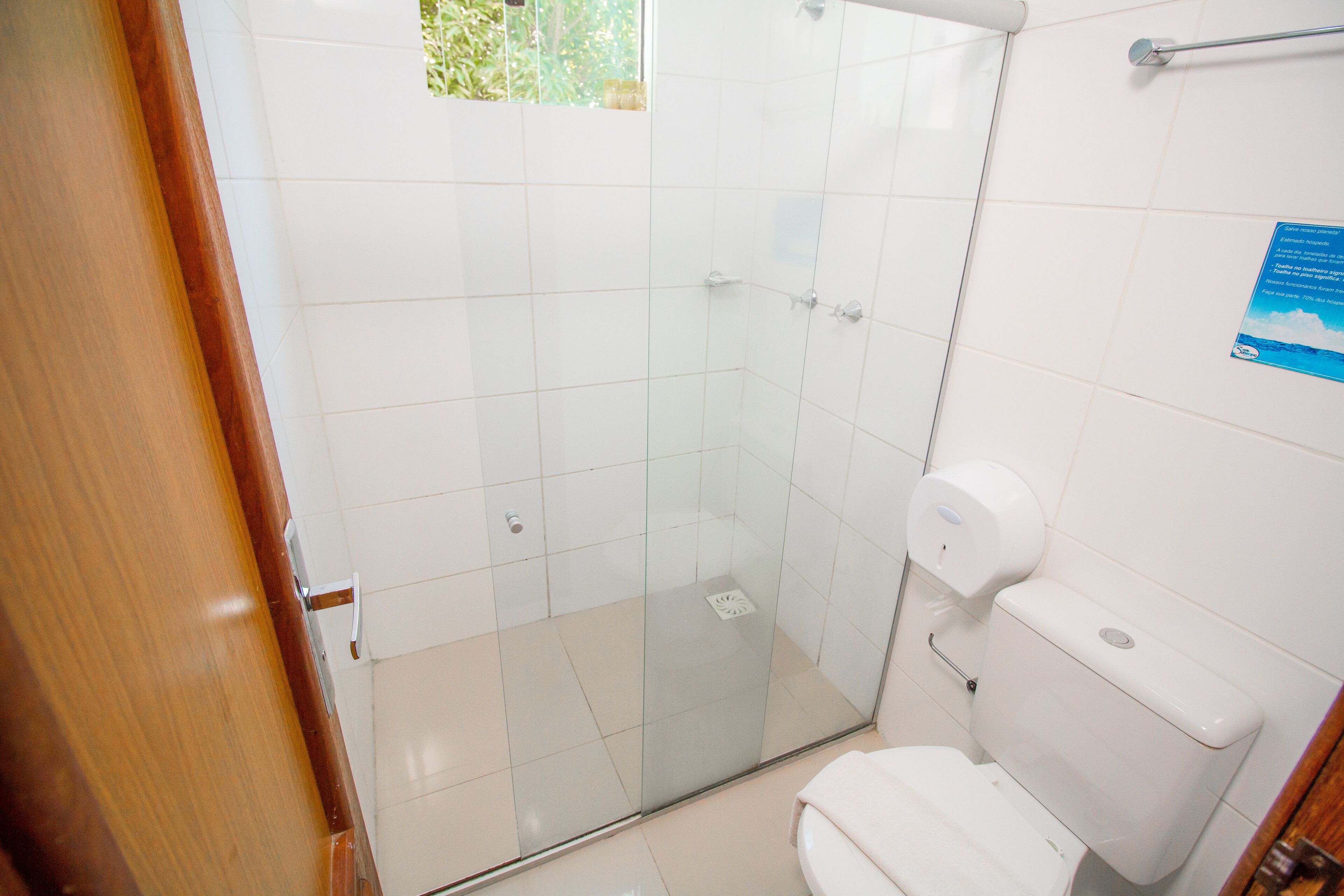 Un baño con cabina de ducha de vidrio, inodoro blanco y puerta de madera.