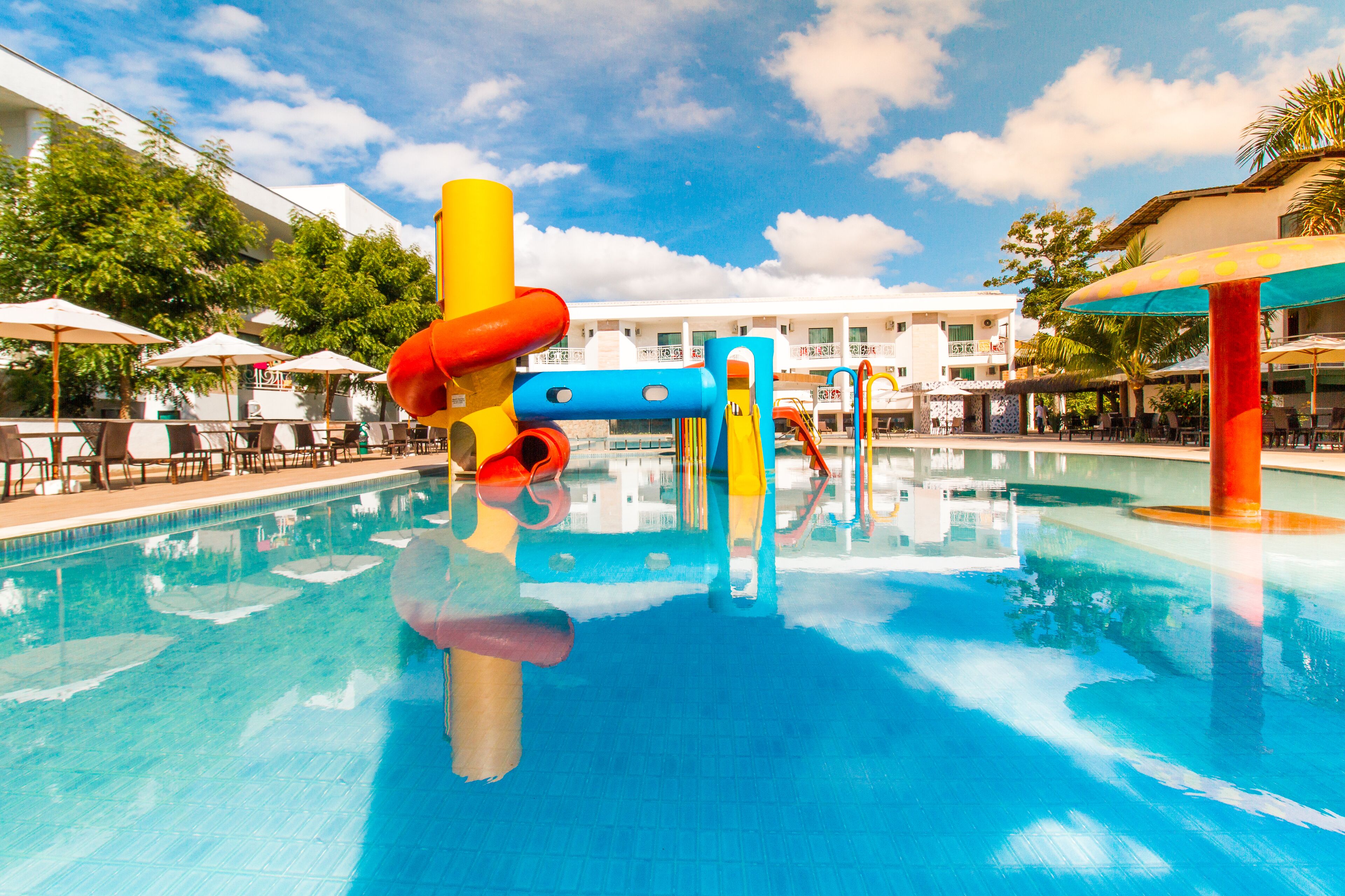 Ein Schwimmbecken mit bunten Wasserrutschen und Sonnenschirmen.