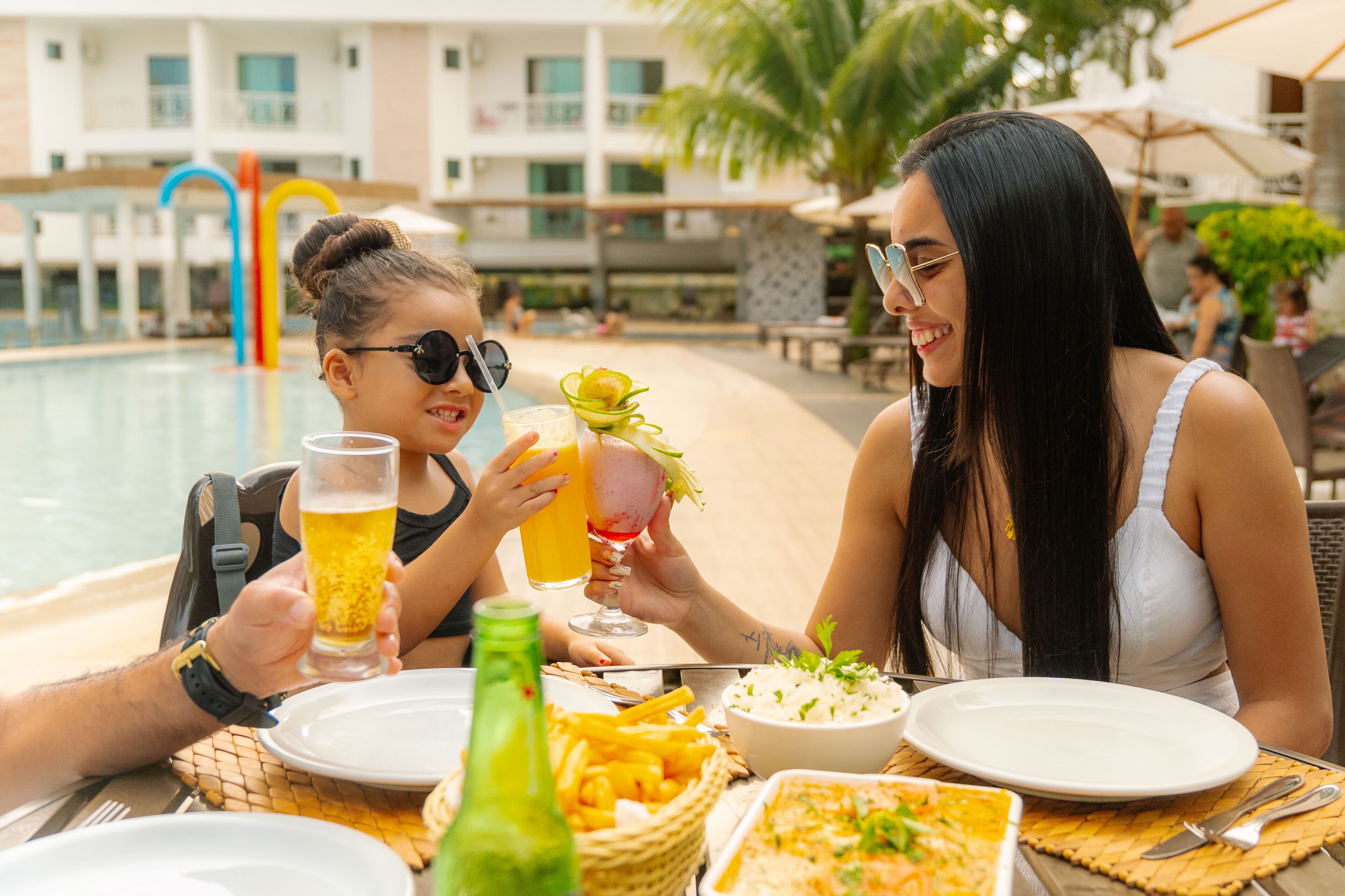A poolside dining area with a table set for two, a bottle of water, and a bowl of salad.