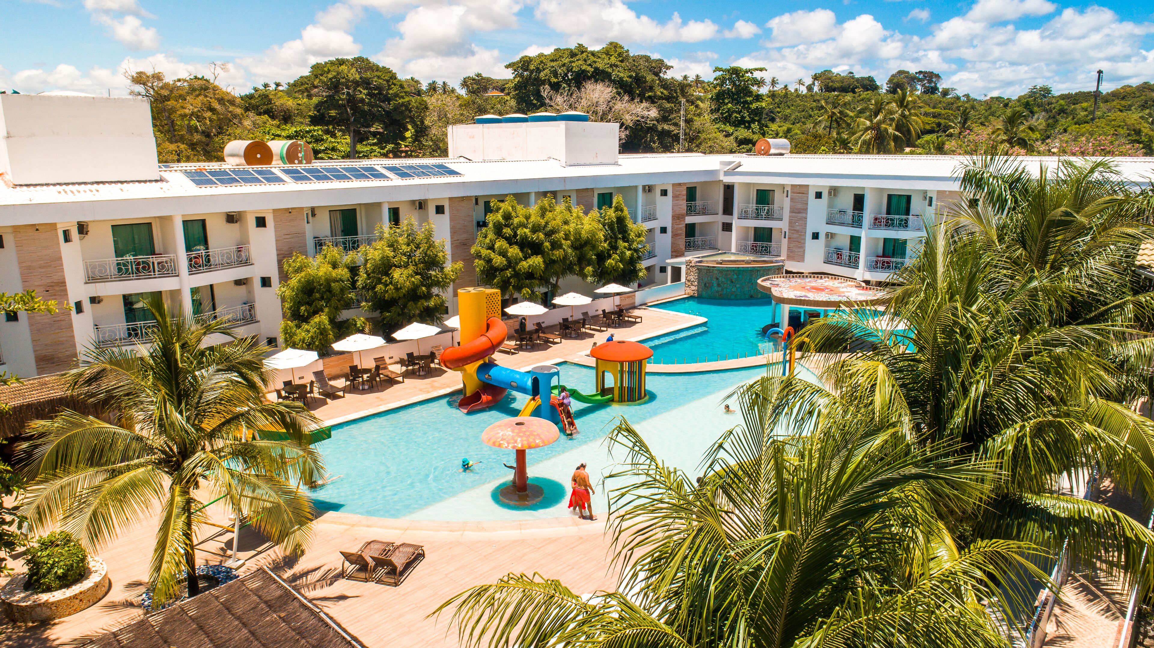 Un hôtel doté d’une piscine, de nombreux balcons et d’une végétation luxuriante.
