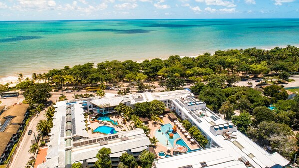 Un resort con varias piscinas, una playa y abundante vegetación.