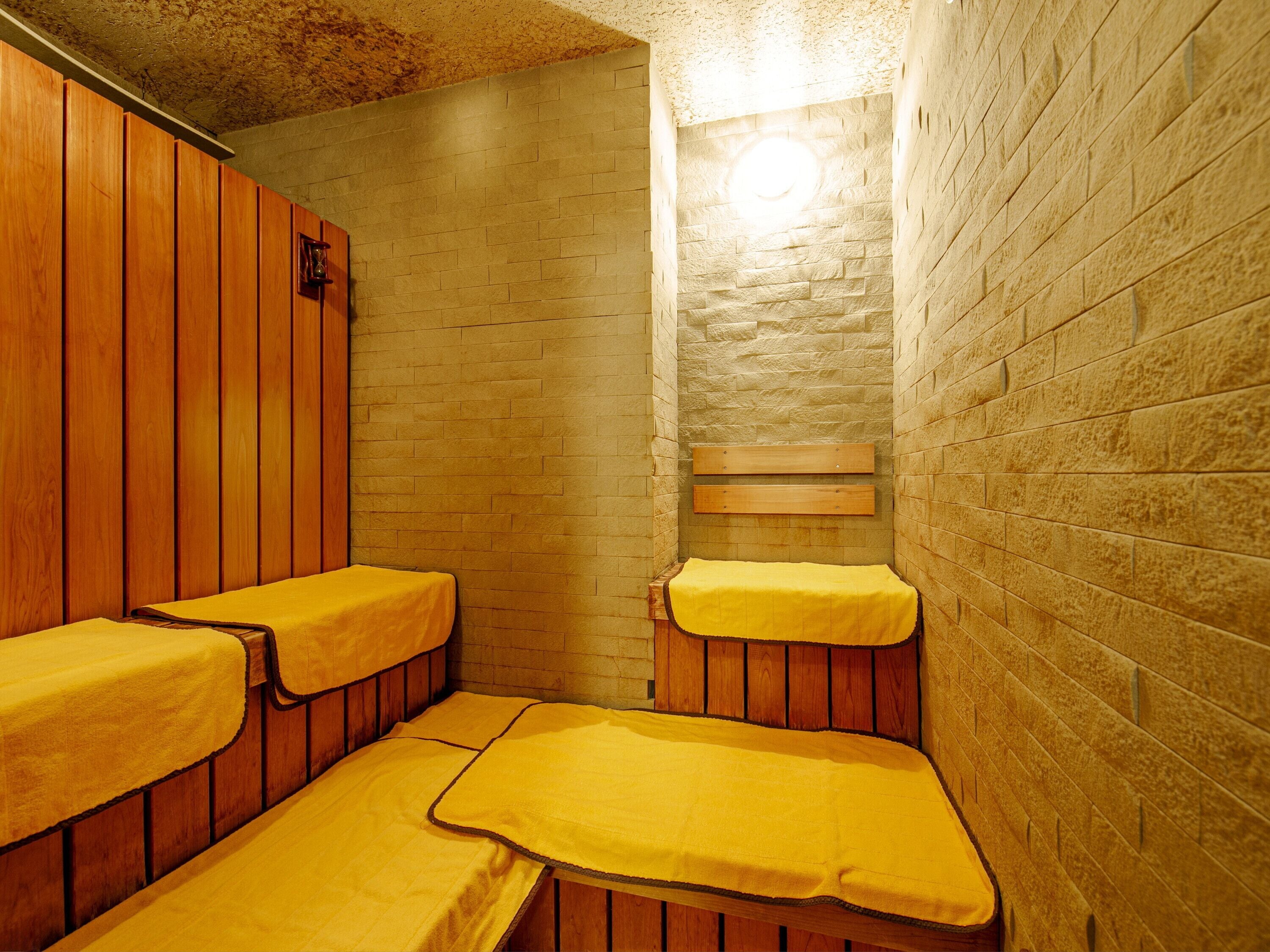 Un sauna avec des bancs en bois et un mur en pierre.