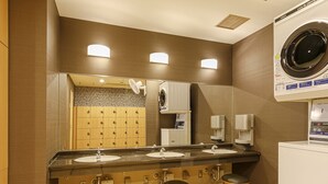 A hotel bathroom with a large mirror, three sinks, a washing machine, and a row of lockers. - APA Hotel Nagoya Marunouchi Ekimae (Nagoya)