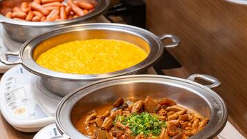 Three metal pots with different dishes on a table, a weighing scale, and a wooden surface.
