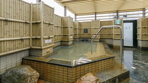A traditional Japanese onsen with wooden walls, a tiled floor, and a stone basin. - APA Hotel Nagoya Marunouchi Ekimae (Nagoya)