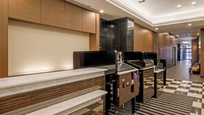 A modern hotel lobby with a check-in counter, seating area, and a check-in machine. - APA Hotel Nagoya Marunouchi Ekimae (Nagoya)