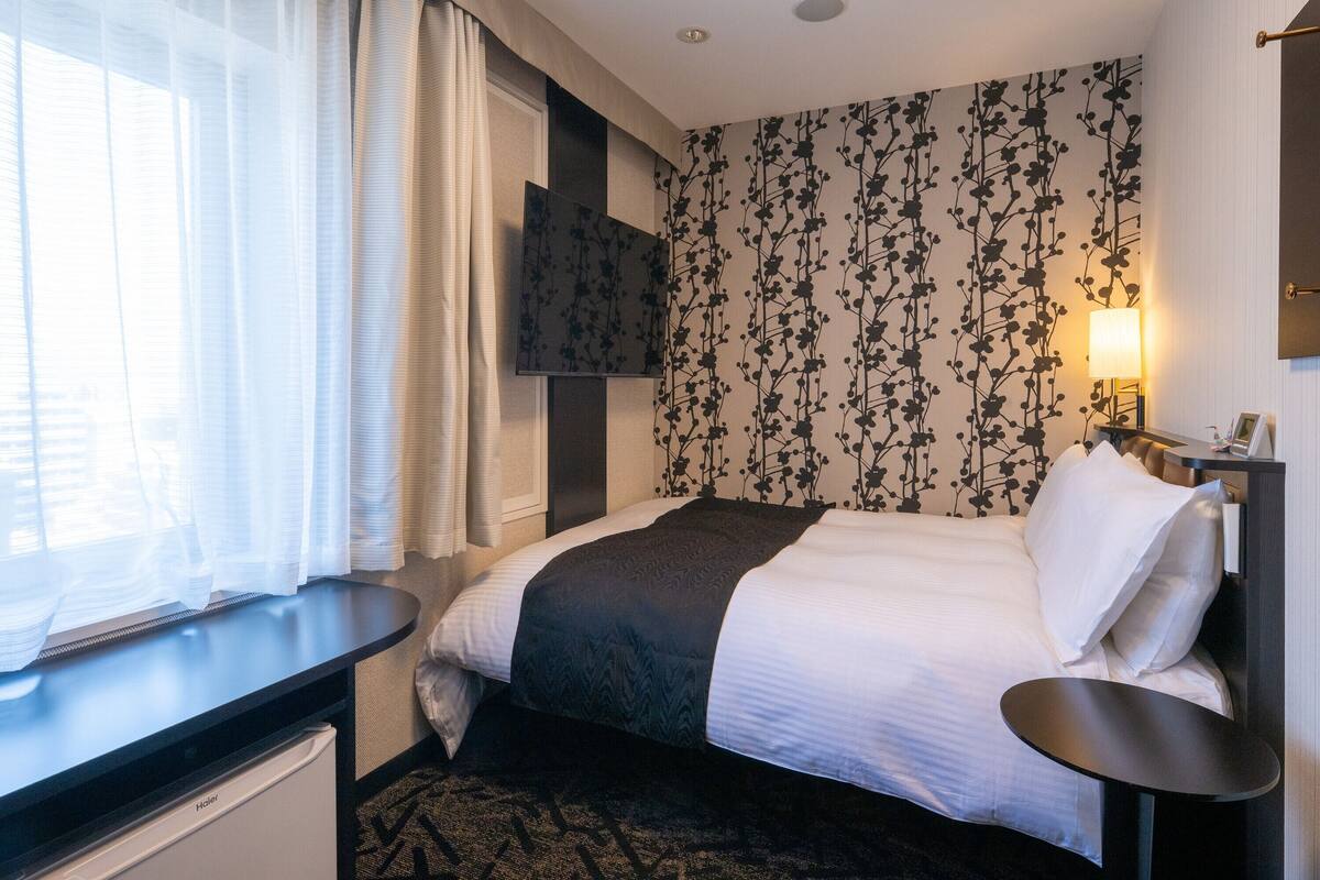 Ein Hotelzimmer mit Bett, Schreibtisch, Fernseher und einer Wand mit Muster.