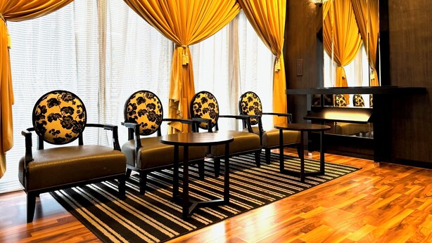 A room with a long table, four chairs with floral upholstery, and a piano. - APA Hotel Kobe Sannomiya (Kobe)