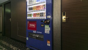 A vending machine with various beverages and snacks, located in a hallway with a door marked 1106. - APA Hotel Kobe Sannomiya (Kobe)