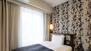 A hotel room with a bed, curtains, a wall-mounted air conditioner, a wall-mounted lamp, and a headboard with a control panel. - APA Hotel Kobe Sannomiya (Kobe)