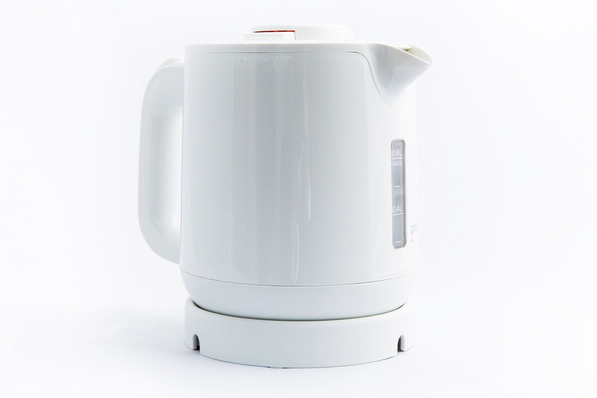 A white electric kettle with a spout and handle, a power cord, and a base with feet.