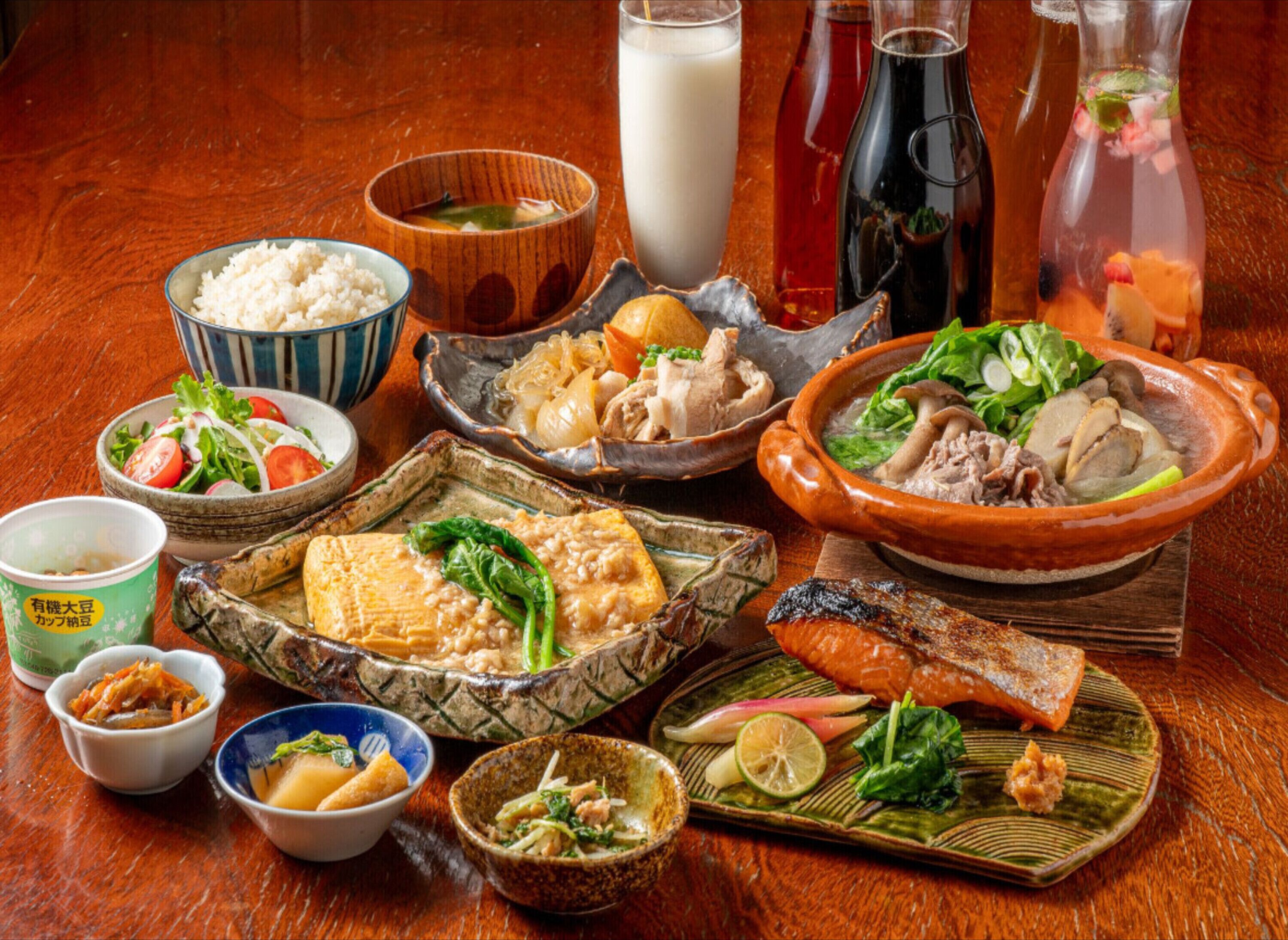 A variety of dishes including rice, soup, and meat, served on a wooden table.