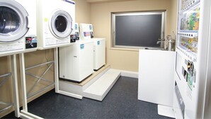 A laundry facility with multiple washing machines and a vending machine.