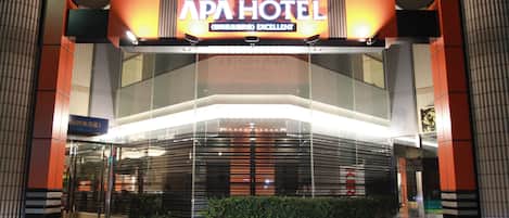 The exterior of the APA Hotel with a prominent sign, modern architecture, and a tiled entrance area.