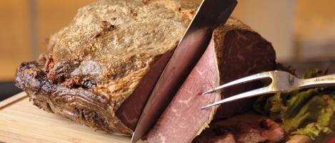A large roast being sliced on a wooden cutting board.