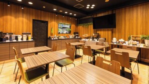 Un restaurante moderno con paredes de paneles de madera, varias mesas y sillas, una zona de cocina con diferentes electrodomésticos y un televisor de pantalla plana montado en la pared.