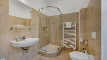A modern bathroom with a glass-enclosed shower, a white sink, and a toilet.