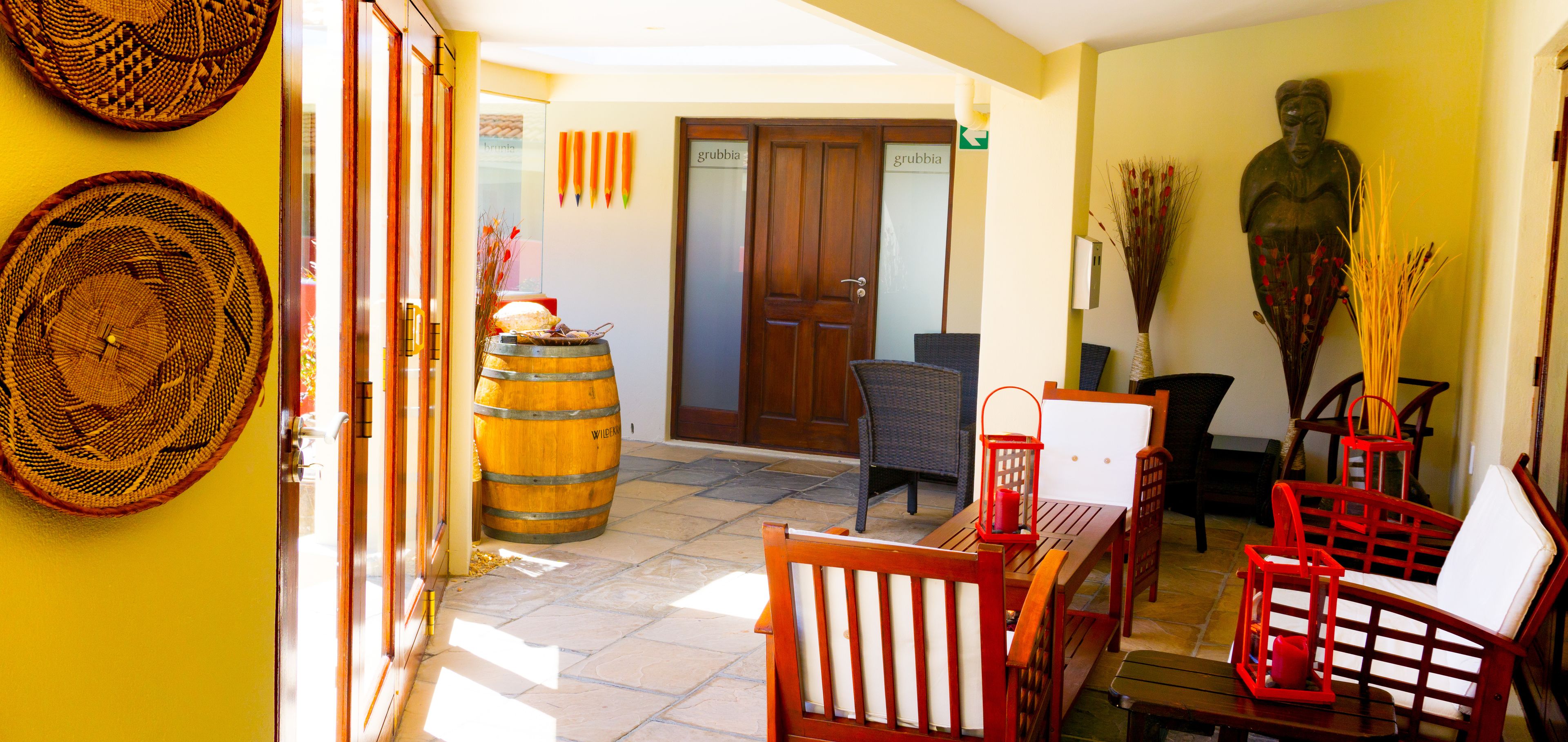 A hotel lobby with a wooden barrel, wicker furniture, and a statue.