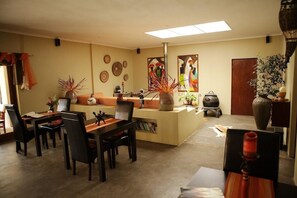 A dining area with a central island, chairs, and a table. There are decorative items on the island and wall art above the island. - Kapensis Guesthouse (Pringle Bay)