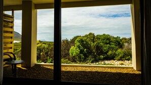 Una habitación con un amplio ventanal que ofrece vistas a un jardín ajardinado y montañas a lo lejos.