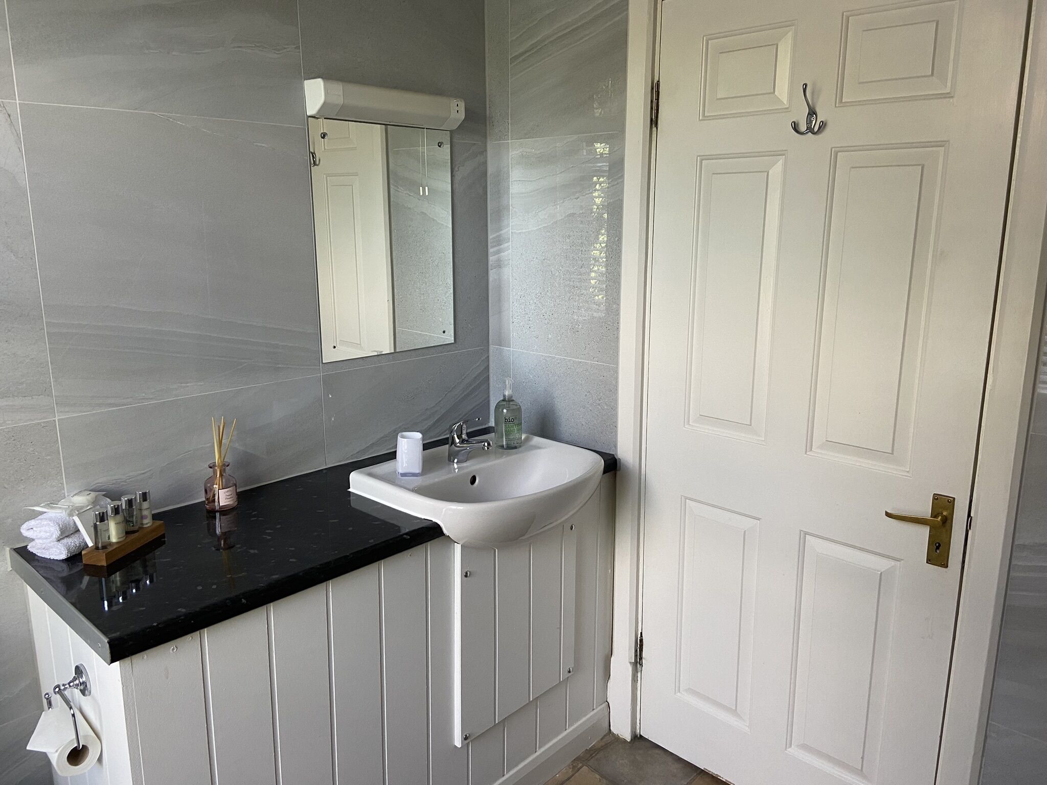 Un bagno con lavandino, specchio e porta bianchi.