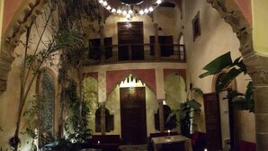 An interior with a central wooden door, arched ceilings, and a chandelier. - Riad Marlinea (Salé)