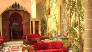 Un intérieur avec des canapés rouges, une table basse et un sol carrelé.
