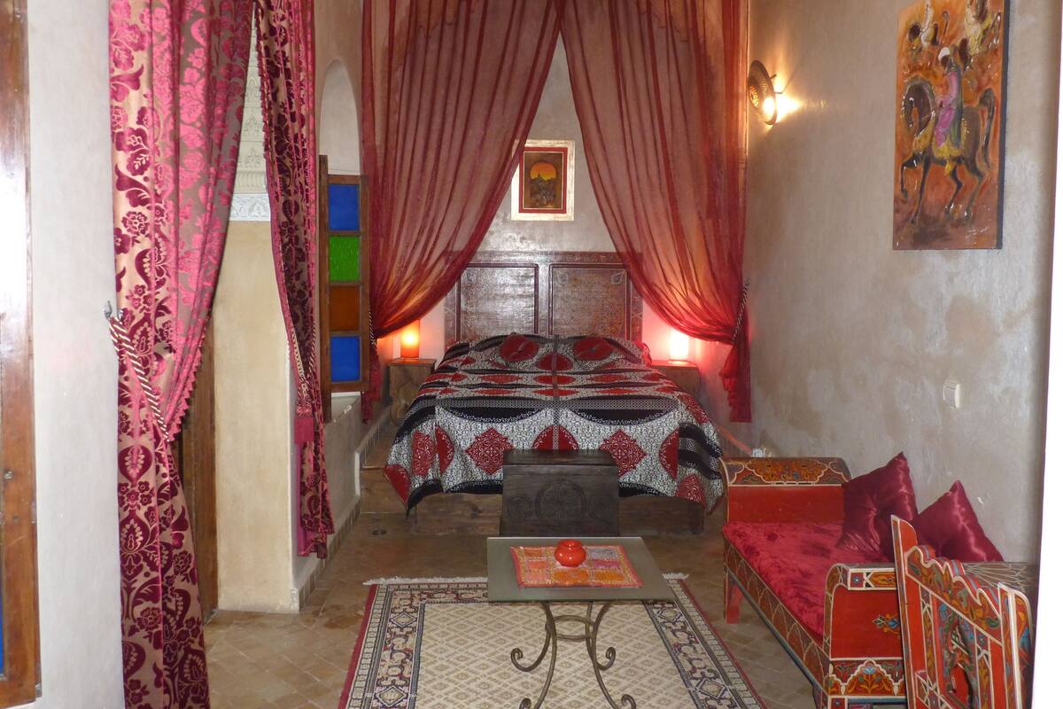Ein traditionell eingerichtetes Zimmer mit einem Bett, einem kleinen Tisch und einer Bank.