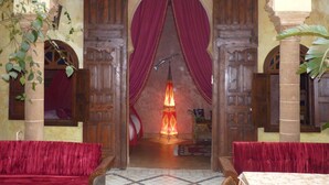 A traditional entrance with wooden doors and red drapes, leading to a warmly lit interior. - Riad Marlinea (Salé)