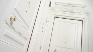 Una puerta blanca con la letra 'Q' dorada y un timbre dorado.