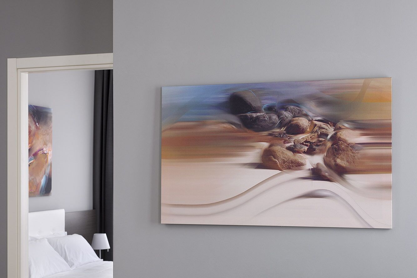 A hotel room with a bed, a nightstand, and a painting on the wall.