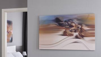 A hotel room with a bed, a nightstand, and a painting on the wall.