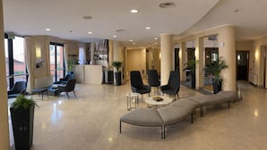 Un vestíbulo de hotel con una zona de estar, una recepción y un bar.