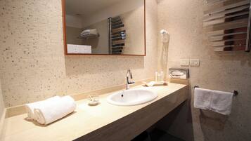 A bathroom with a sink, mirror, towel rack, and a wall-mounted hairdryer.