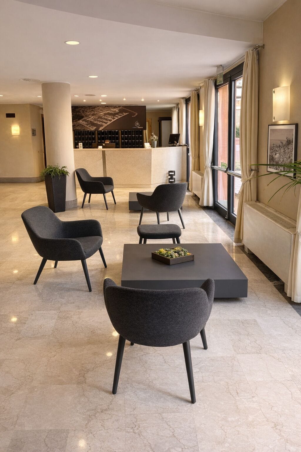 Un hall d’entrée moderne doté d’un comptoir de réception, d’un espace salon et de grandes fenêtres.
