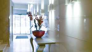 A modern hallway with a red bowl containing flowers, a bench, and a door at the end. - Belgrade Art Hotel, a member of Radisson Individuals (Belgrade)