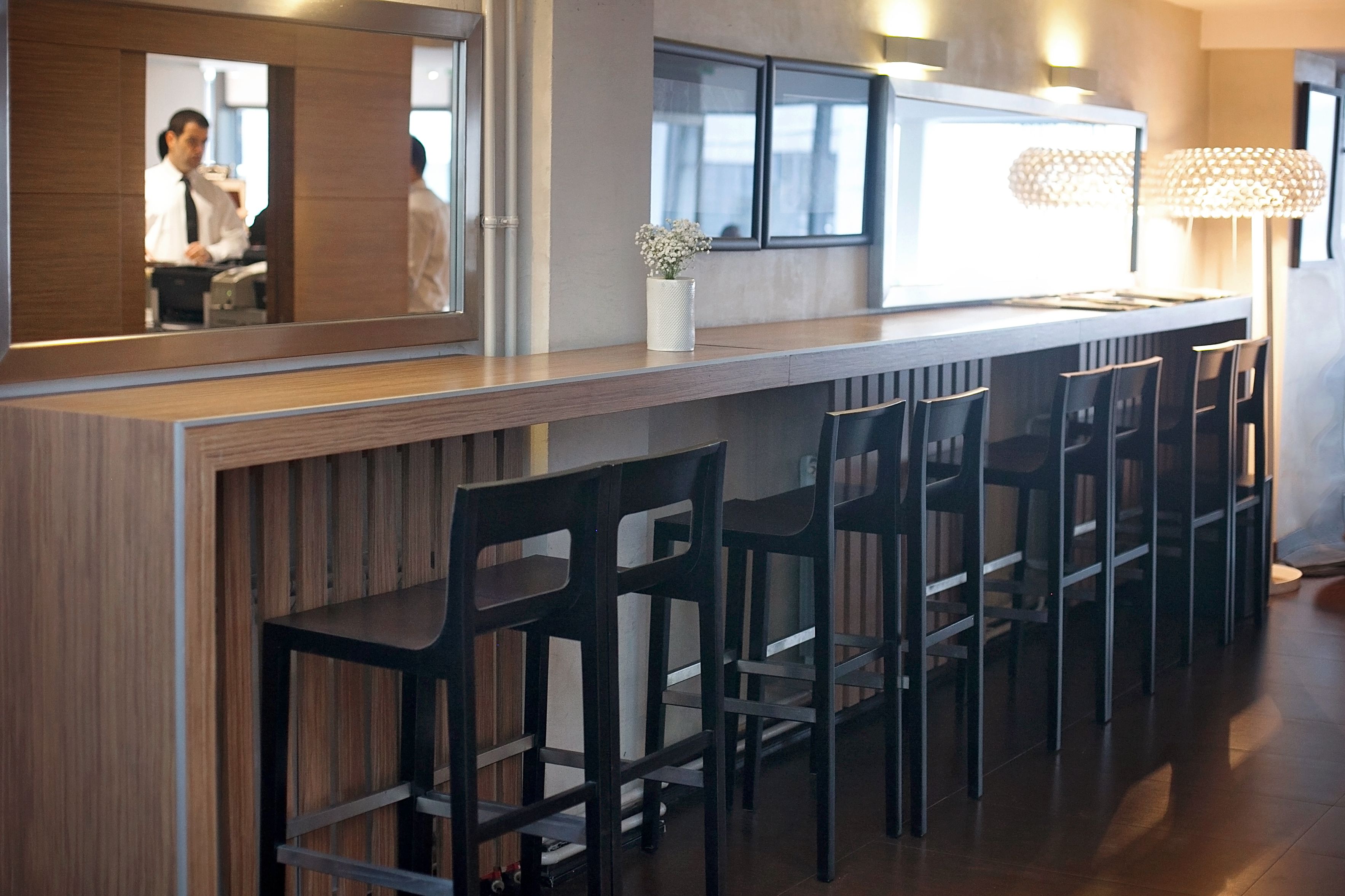A bar area with wooden bar counter and black bar stools.
