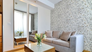 A modern living room with a grey sofa, a wooden coffee table, and a patterned wallpaper. - Belgrade Art Hotel, a member of Radisson Individuals (Belgrade)