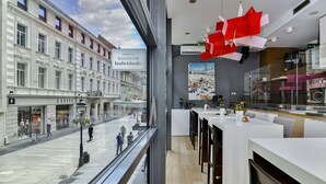 A modern hotel interior with a large window overlooking a busy street, a contemporary kitchen area, and a seating space with a view. - Belgrade Art Hotel, a member of Radisson Individuals (Belgrade)