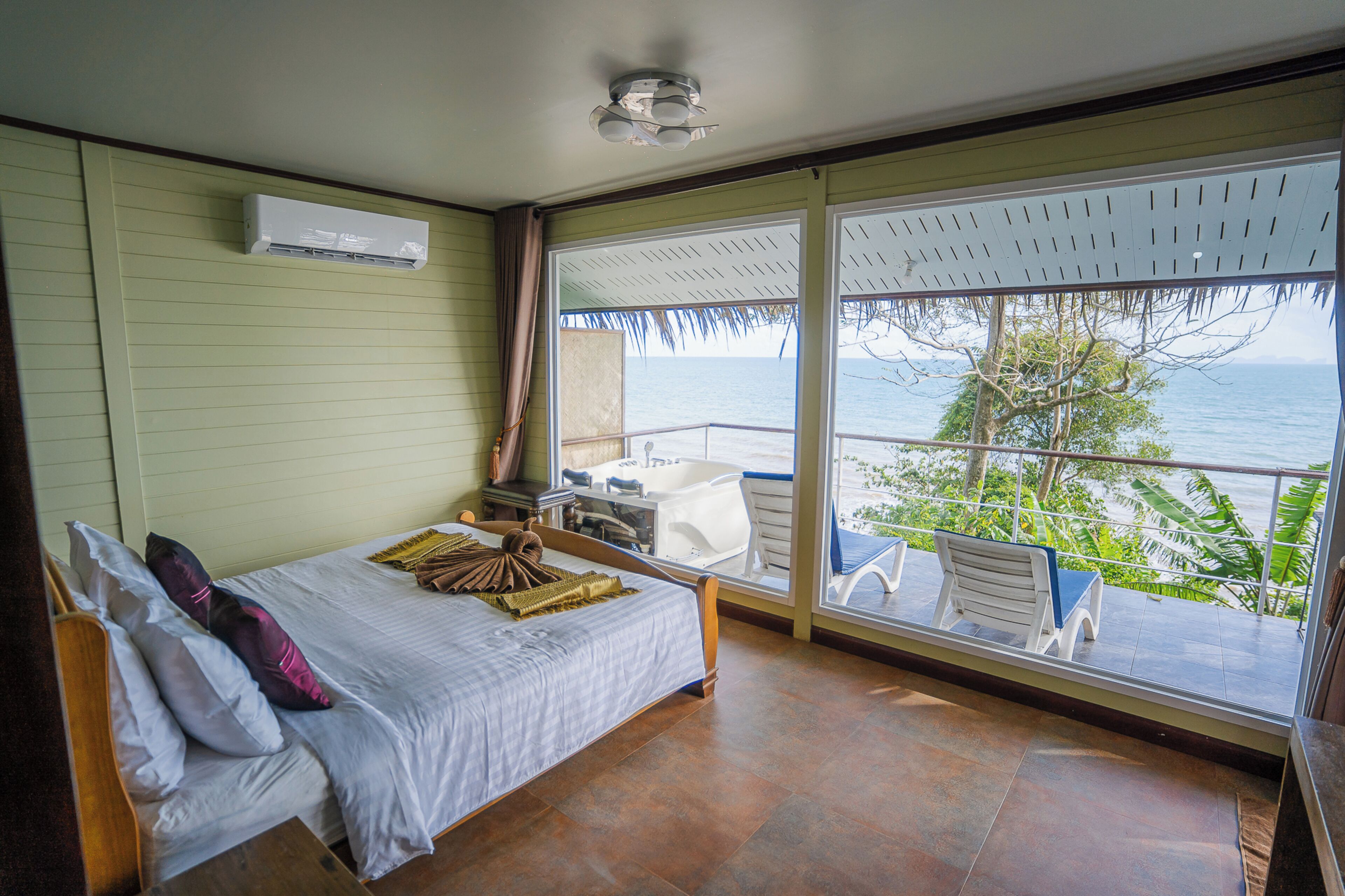 A bedroom with a bed, a window with a view of the sea, and a balcony with a chair.