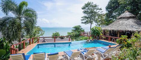 Een buitenzwembad, parasols bij het zwembad en ligstoelen