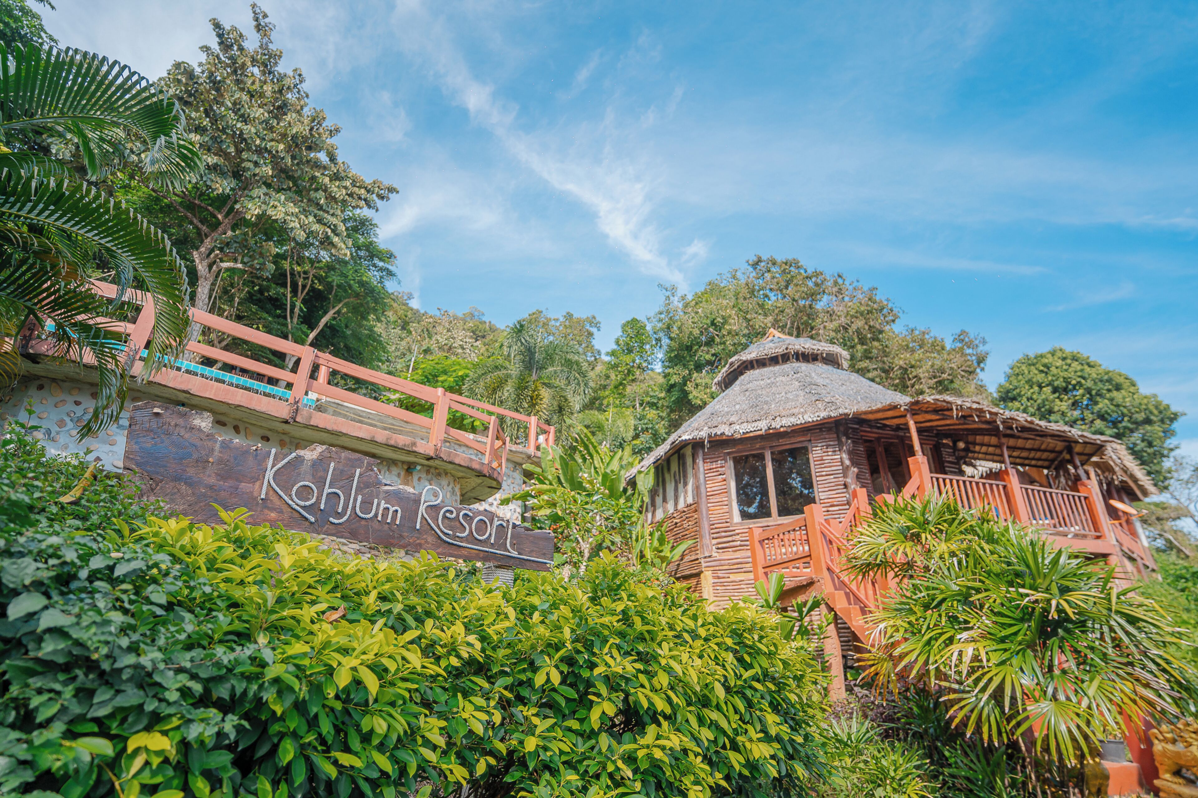 A resort with a wooden structure, a bridge, and lush greenery.