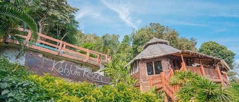 A resort with a wooden structure, a bridge, and lush greenery.