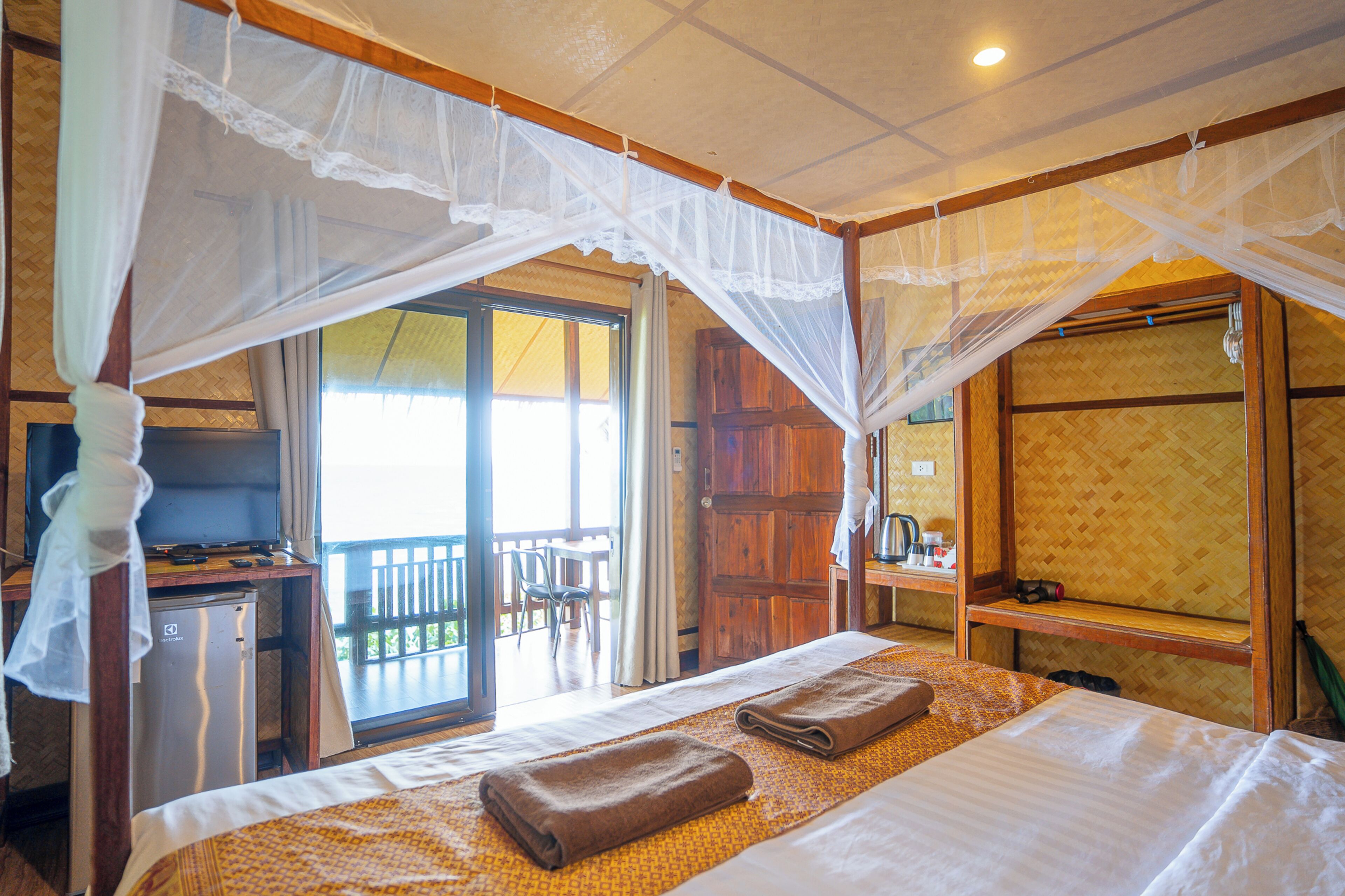 A room with a bed, a desk, a television, and a balcony with a view.