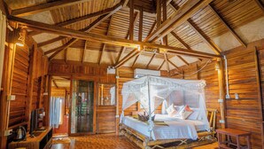 Una cabaña de madera con cama con dosel, televisión y piso de madera.
