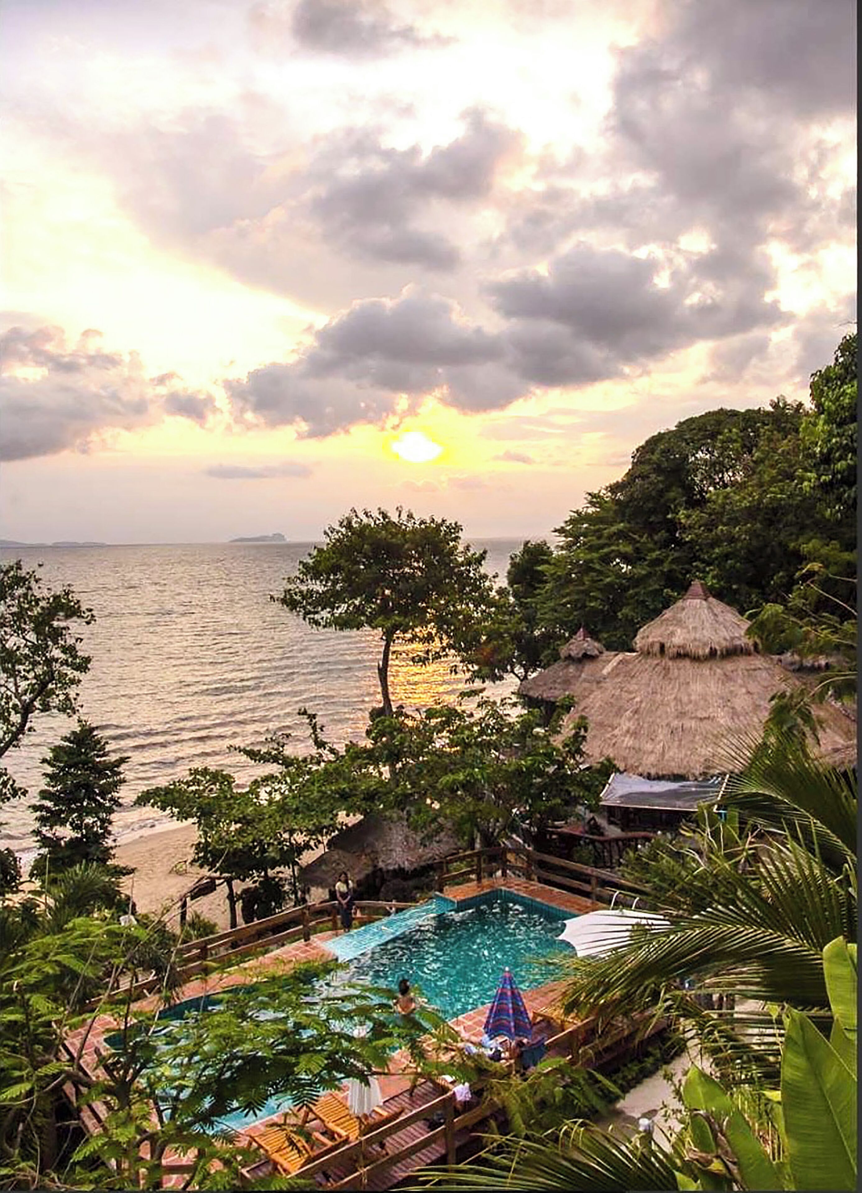 A pool area with a view of the sea and sunset.