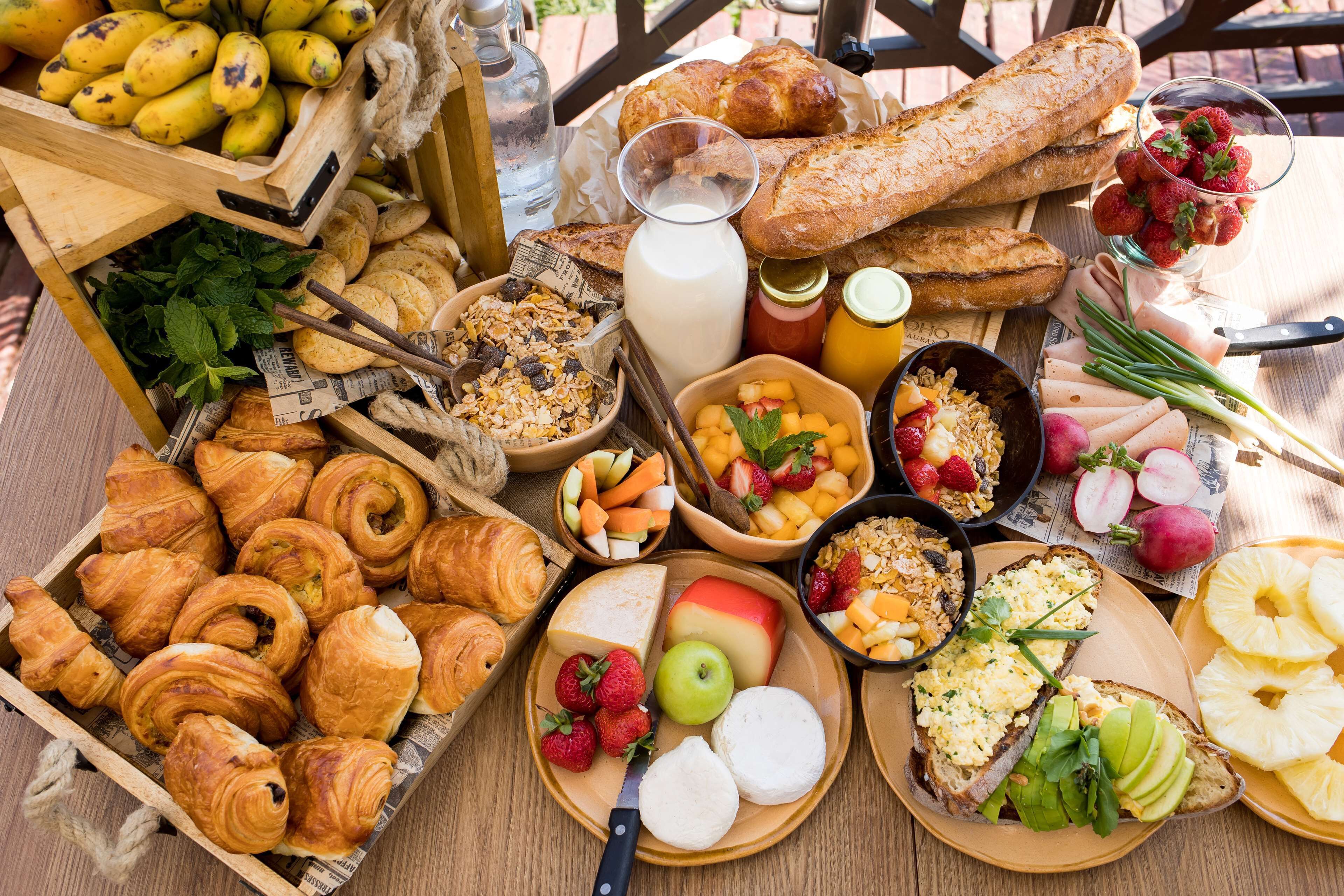 A variety of breakfast items including pastries, fruits, and cheeses on a wooden table.