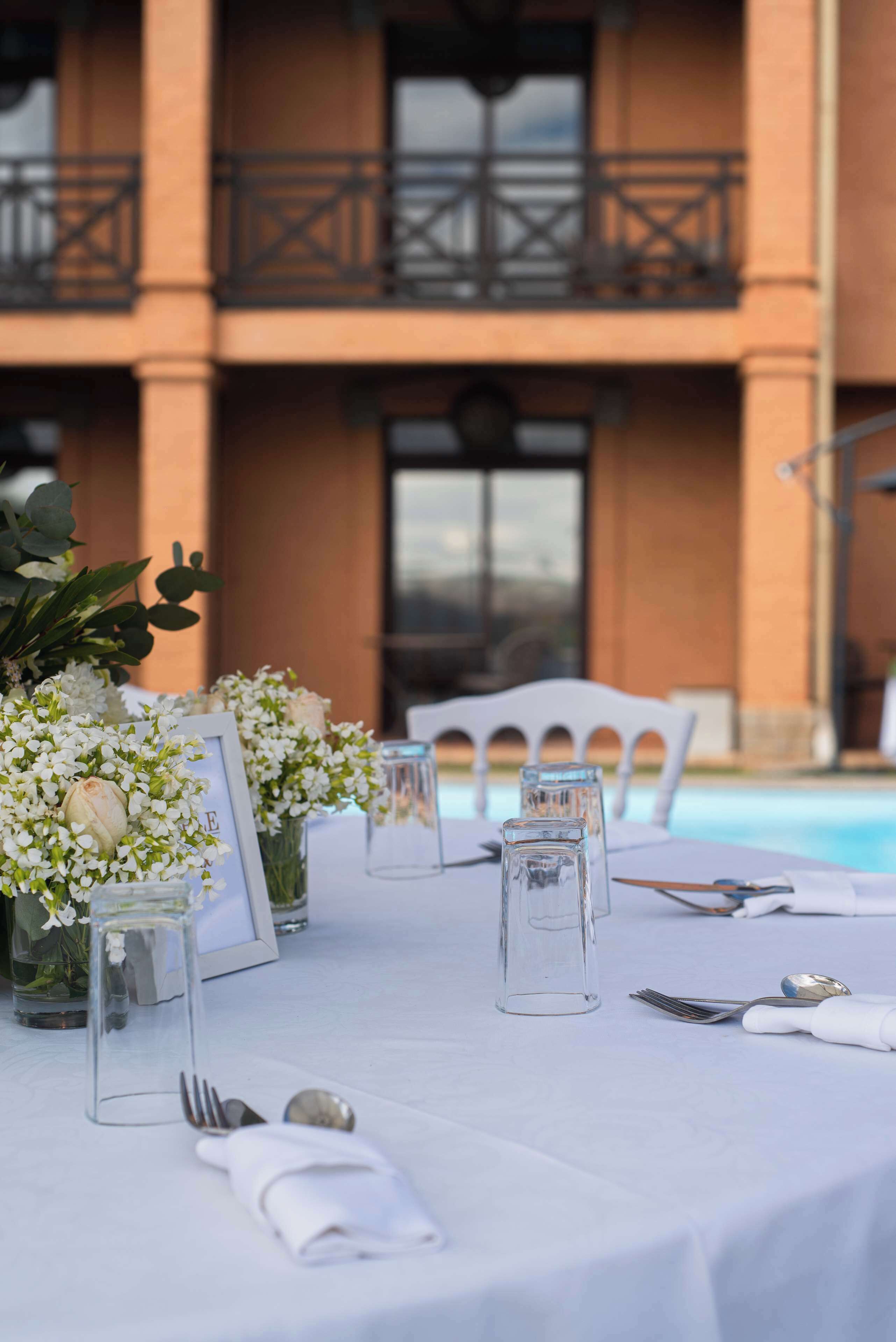 A table set for dining with a pool in the background.